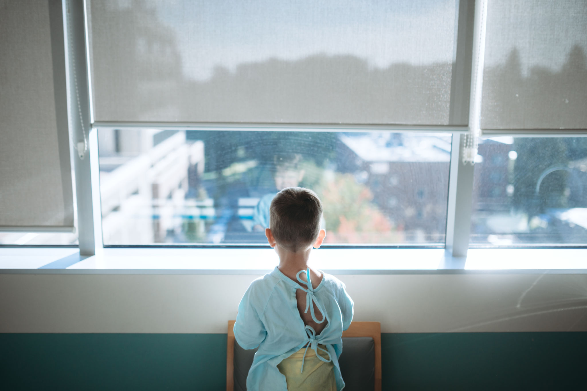 Fotografie a unui copil in spital care se uita pe geam